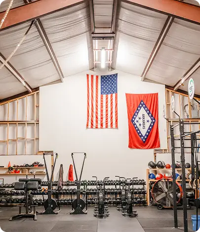 The Paradigm Fitness gym floor with dumbbells, rigs and Arkansas flag
