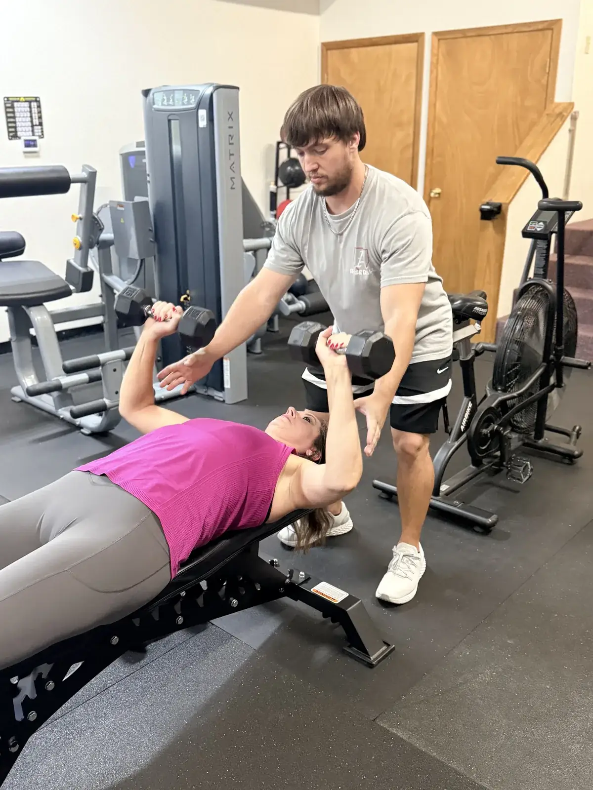 Coach spotting a member during a dumbbell press
